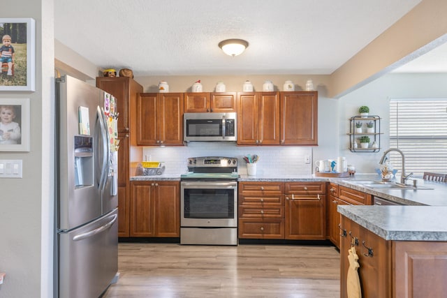 kitchen featuring appliances with stainless steel finishes, backsplash, light hardwood / wood-style floors, and sink