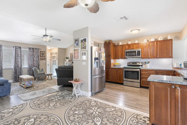 kitchen featuring light wood-type flooring, stainless steel appliances, tasteful backsplash, and ceiling fan