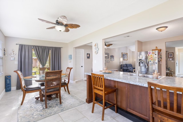 tiled dining room featuring ceiling fan and sink