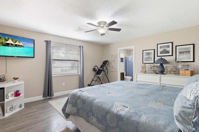 bedroom with a textured ceiling, light wood-type flooring, ensuite bathroom, and ceiling fan