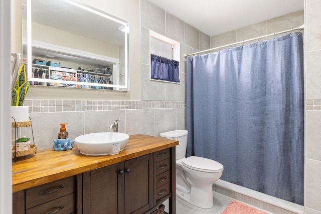 bathroom with a shower with curtain, vanity, toilet, and tile walls