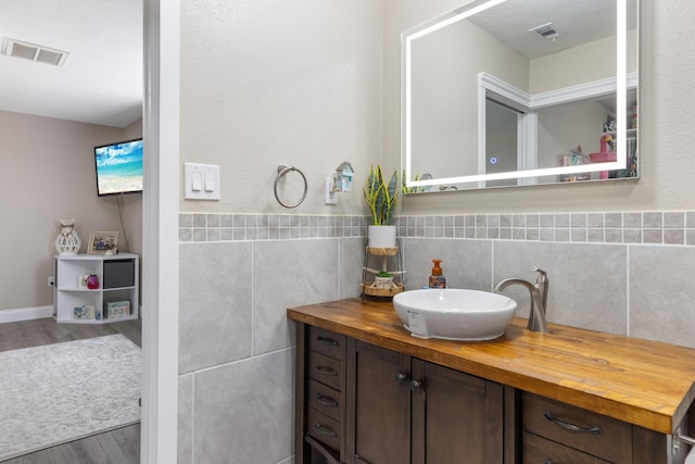 bathroom featuring hardwood / wood-style floors, vanity, and tile walls