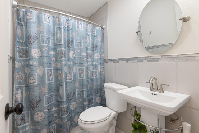 bathroom featuring toilet, tile walls, curtained shower, and sink