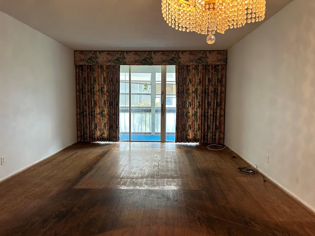 empty room featuring a chandelier and hardwood / wood-style flooring