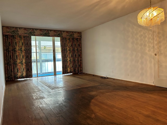 empty room featuring dark hardwood / wood-style floors and a notable chandelier