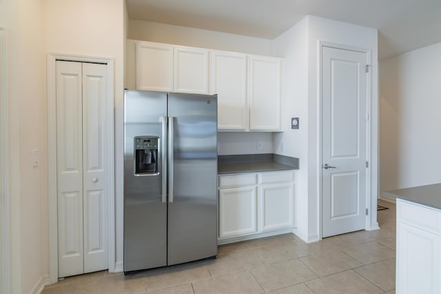 kitchen with white cabinets, stainless steel fridge, and light tile patterned floors