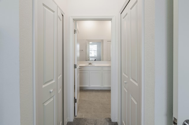 hall featuring sink and light tile patterned floors