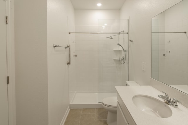 bathroom with tiled shower, vanity, tile patterned flooring, and toilet