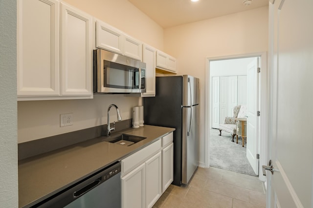 kitchen with light tile patterned flooring, sink, white cabinets, and stainless steel appliances