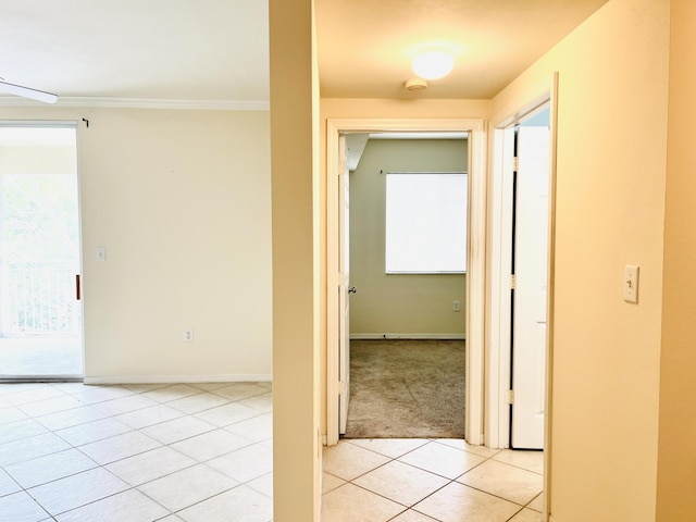 hall featuring light tile patterned floors and crown molding