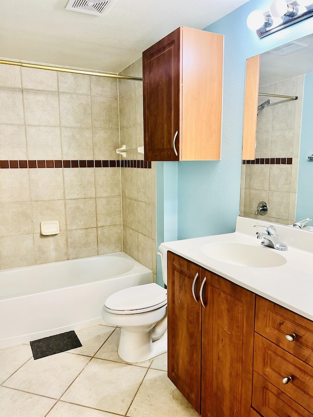 full bathroom with a textured ceiling, vanity, tile patterned flooring, toilet, and tiled shower / bath