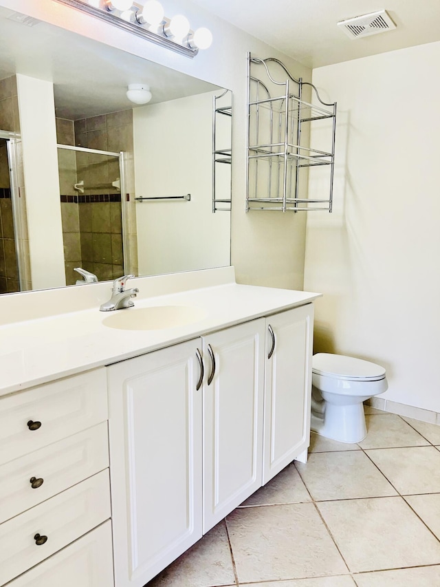 bathroom with tile patterned flooring, vanity, toilet, and walk in shower