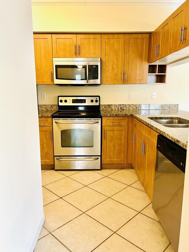 kitchen featuring light tile patterned floors, sink, stainless steel appliances, and stone countertops