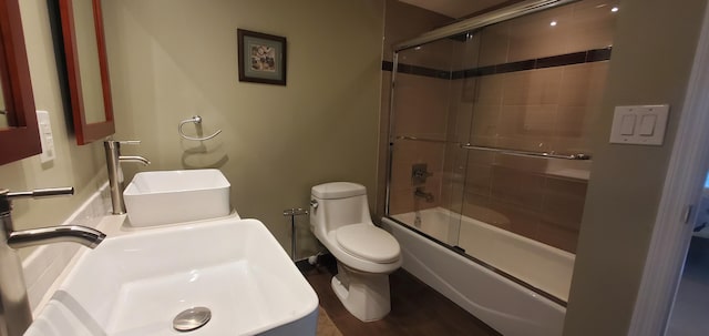 full bathroom featuring hardwood / wood-style floors, toilet, combined bath / shower with glass door, and sink