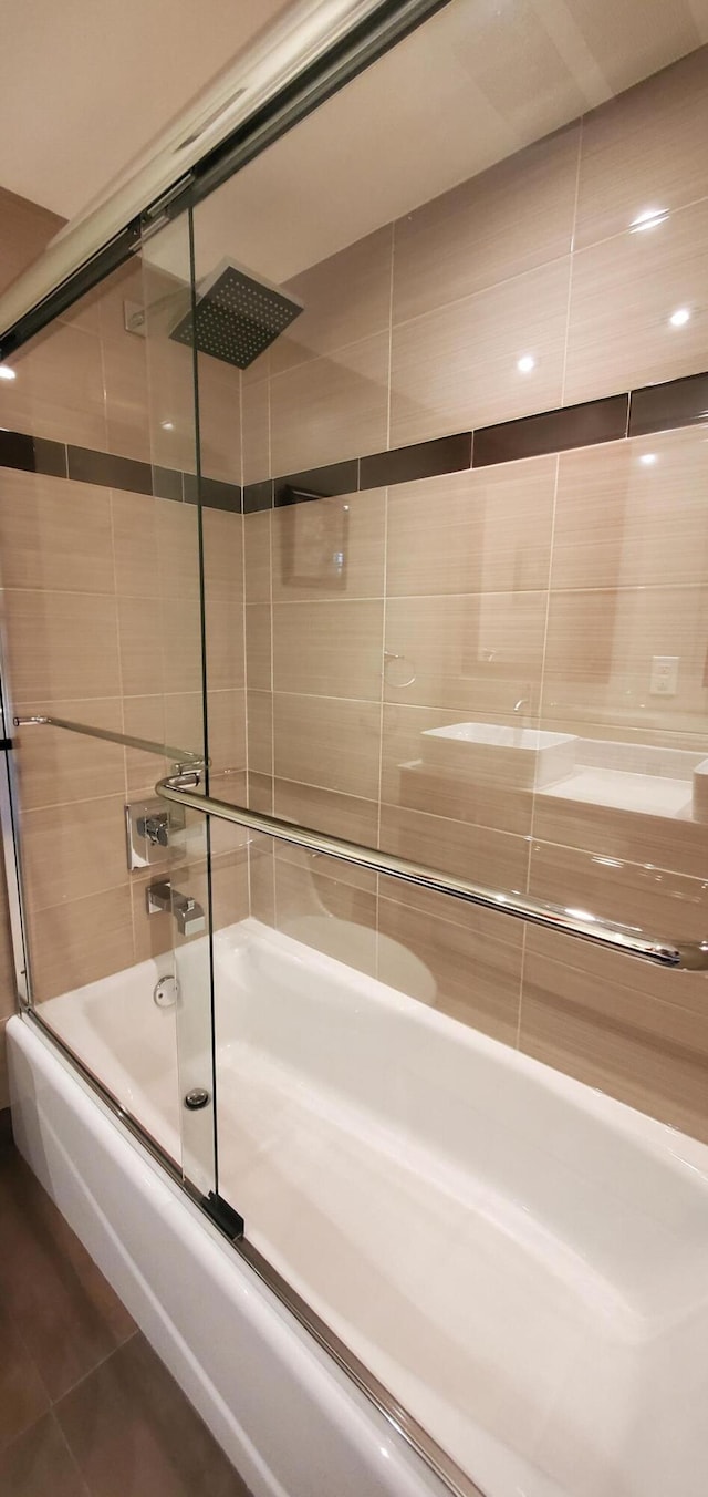 bathroom with combined bath / shower with glass door and tile patterned flooring