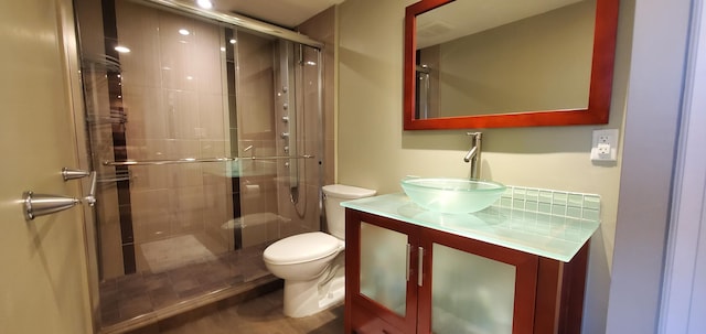 bathroom featuring a shower with door, vanity, and toilet