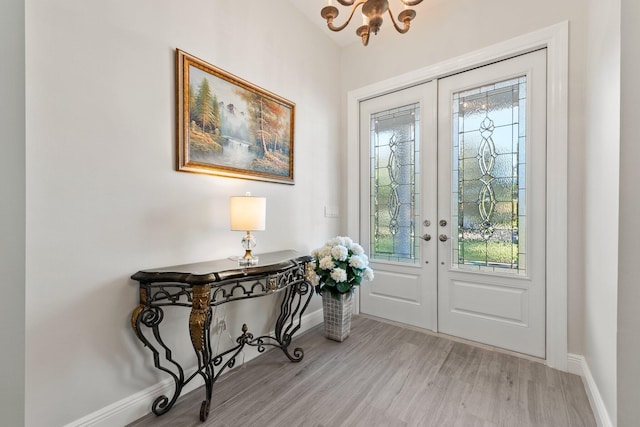 entryway featuring french doors, light hardwood / wood-style flooring, a wealth of natural light, and a notable chandelier