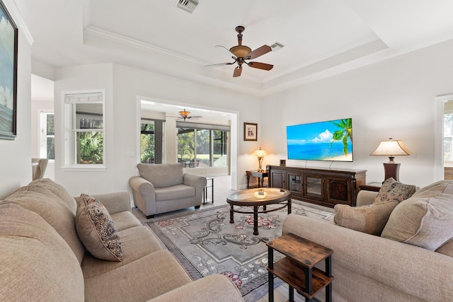 living room with a tray ceiling, ceiling fan, and crown molding