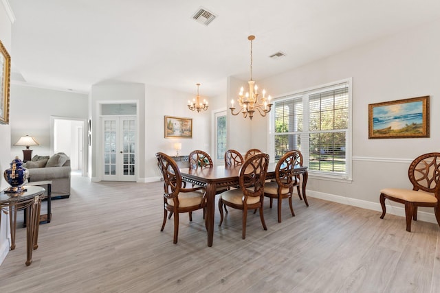 dining area with french doors, light wood-type flooring, and a notable chandelier