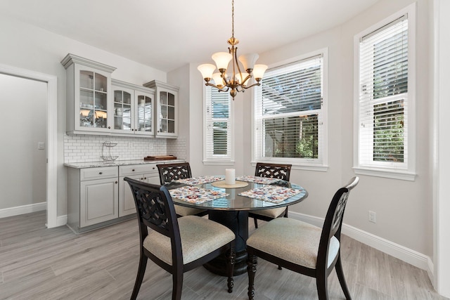 dining area with light wood-type flooring and an inviting chandelier