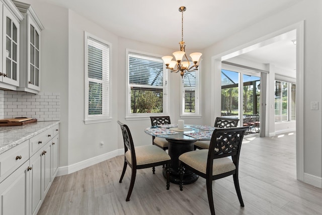 dining space featuring light hardwood / wood-style floors, plenty of natural light, and a notable chandelier