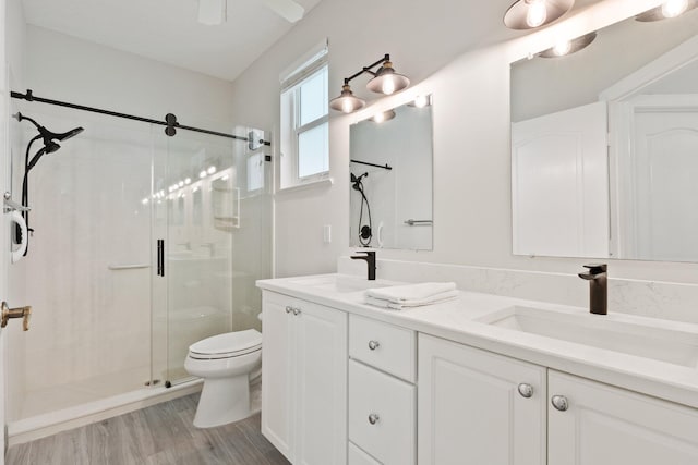 bathroom featuring vanity, hardwood / wood-style flooring, toilet, and a shower with shower door