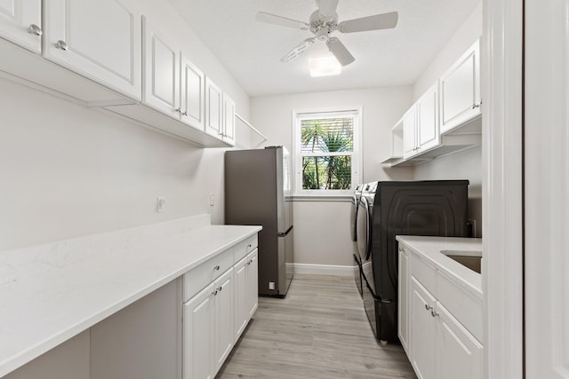 washroom with separate washer and dryer, ceiling fan, cabinets, and light wood-type flooring