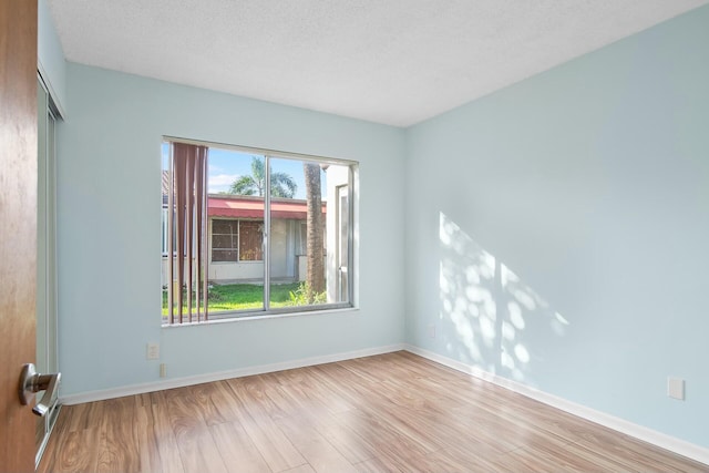 unfurnished room featuring a textured ceiling and light hardwood / wood-style flooring