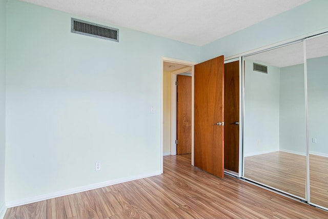 unfurnished bedroom featuring light wood-type flooring and a closet