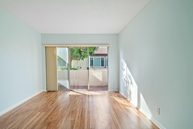 unfurnished room featuring a textured ceiling and light hardwood / wood-style flooring