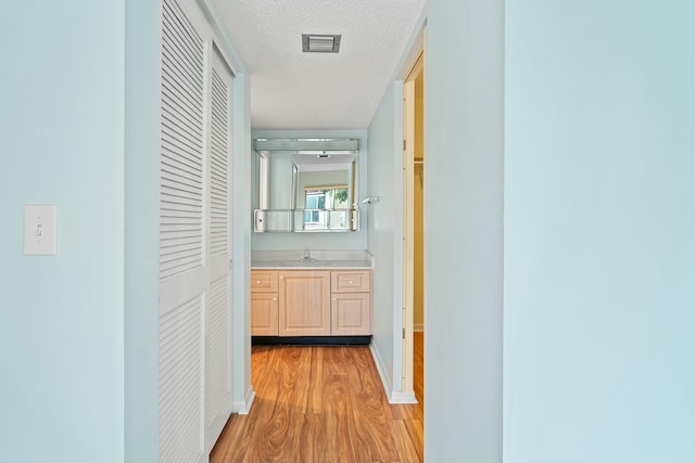 corridor featuring light hardwood / wood-style flooring, a textured ceiling, and sink