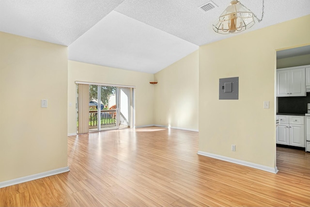 unfurnished living room with lofted ceiling, electric panel, light hardwood / wood-style flooring, a textured ceiling, and a notable chandelier