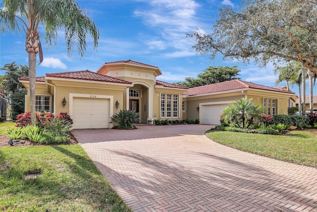 mediterranean / spanish house featuring a garage and a front lawn