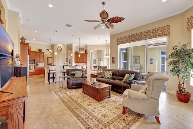 living area featuring a ceiling fan, arched walkways, visible vents, and crown molding