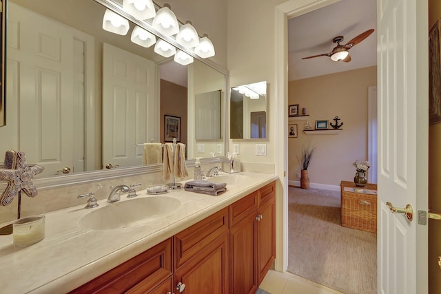 bathroom featuring ceiling fan, double vanity, a sink, and baseboards