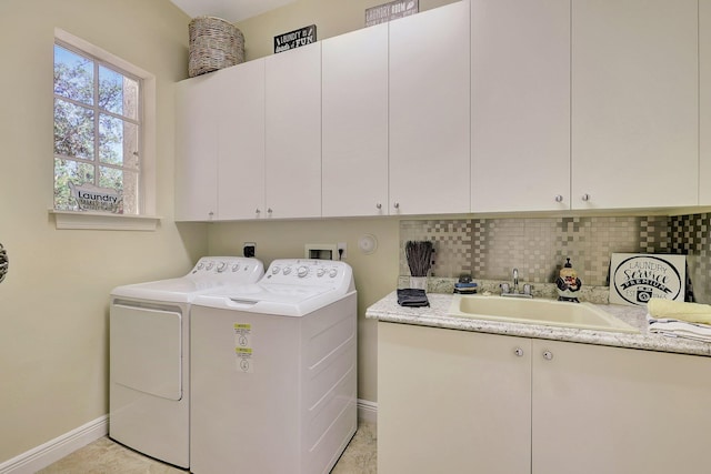 clothes washing area with separate washer and dryer, a sink, cabinet space, and baseboards