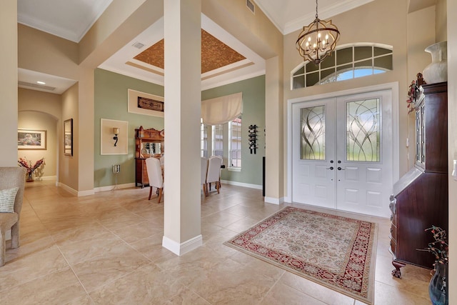 foyer with an inviting chandelier, baseboards, visible vents, and ornamental molding