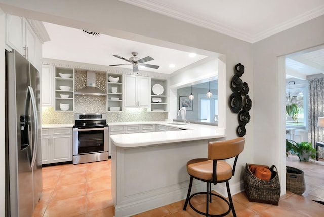 kitchen with backsplash, white cabinets, wall chimney range hood, appliances with stainless steel finishes, and kitchen peninsula