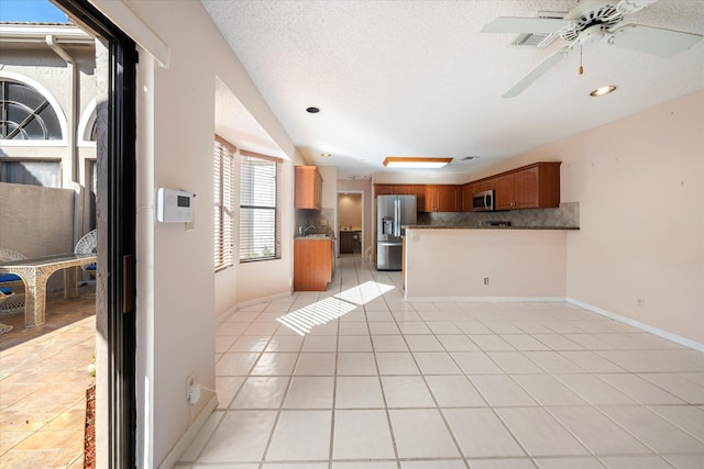 kitchen with ceiling fan, tasteful backsplash, light tile patterned flooring, kitchen peninsula, and stainless steel appliances