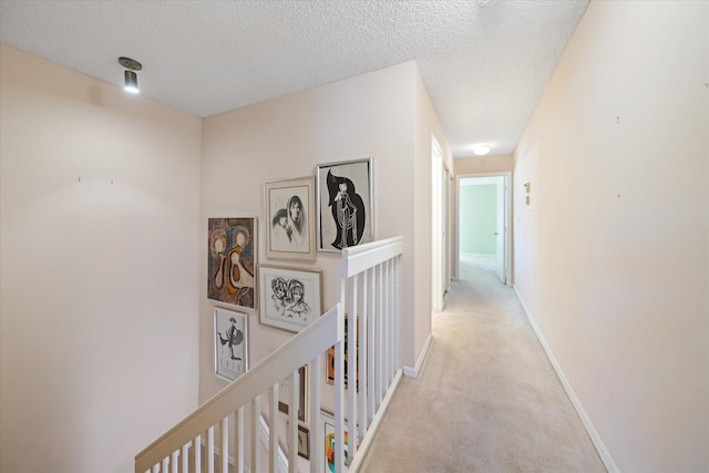 corridor with light carpet and a textured ceiling