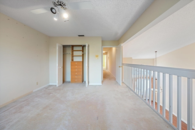 carpeted spare room with a textured ceiling, vaulted ceiling, and ceiling fan