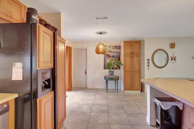 kitchen featuring black fridge, light tile patterned flooring, and pendant lighting