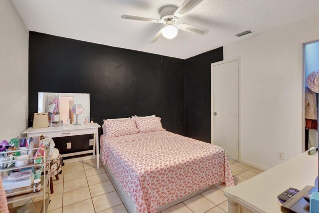 tiled bedroom with ceiling fan and a textured ceiling