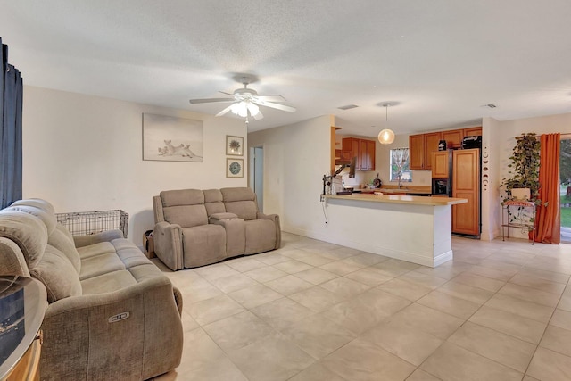 living room with ceiling fan, light tile patterned floors, and a textured ceiling