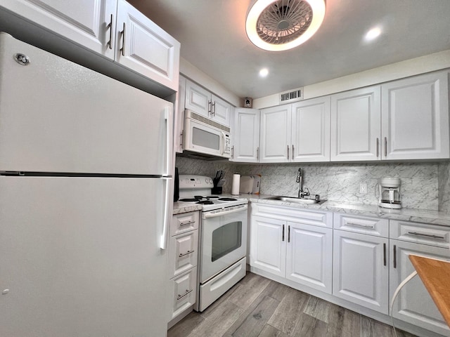 kitchen with white cabinetry, sink, white appliances, and light hardwood / wood-style flooring