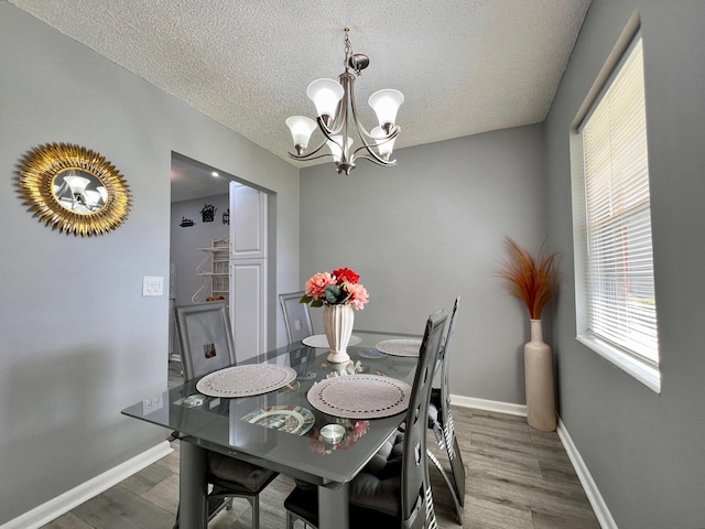 dining room with a textured ceiling, a chandelier, and dark hardwood / wood-style floors