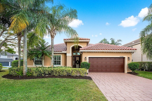 mediterranean / spanish-style home featuring a front yard and a garage