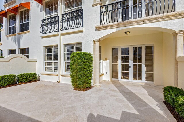 property entrance with a patio area, a balcony, and french doors