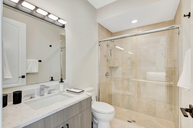 bathroom with vanity, toilet, and a shower with door