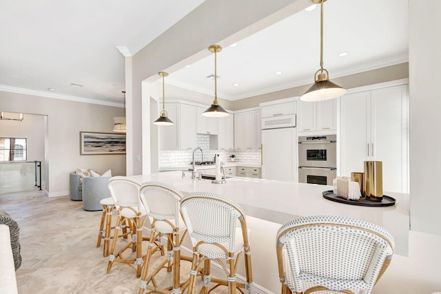 kitchen with stainless steel double oven, crown molding, paneled built in refrigerator, white cabinets, and hanging light fixtures